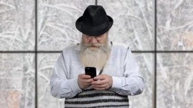 Yaşlı beyaz adam akıllı telefonunda uygulama kullanıyor..