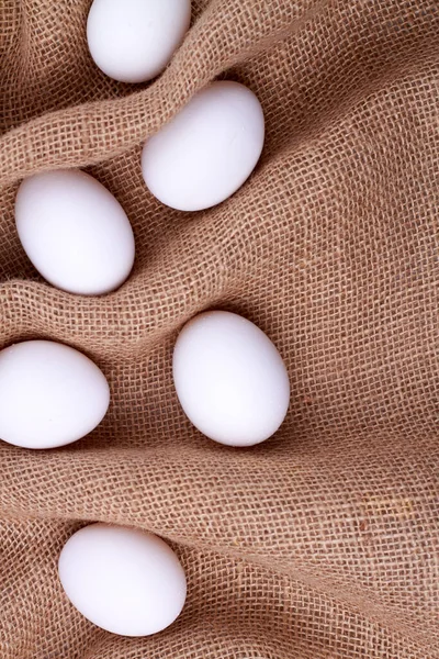Ett gäng vita ägg på en rustik juteväv. — Stockfoto