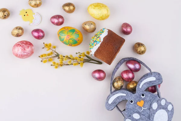 Von oben farbige Eier mit Cupcake, Weide und Hase auf weißem Hintergrund. — Stockfoto