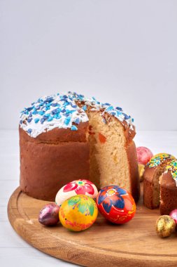 Renkli yumurtalar ve beyaz arka planda ev yapımı paskalya pastaları..