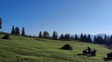 Yeşil tepede ATV bisikleti süren üç adam..