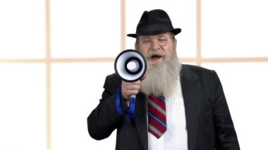 Yaşlı sakallı adam megafonla anons yapıyor..