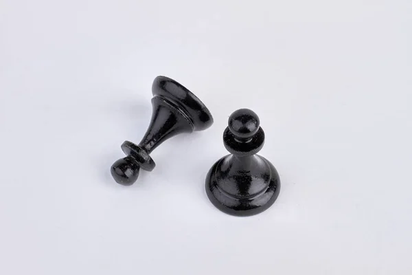 Peão preto peça de xadrez fica perto de peça de xadrez caído. — Fotografia de Stock