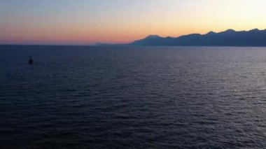 Akşam batımı manzaralı deniz ve dağlar üzerinde.