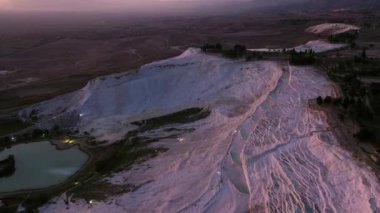 Gün batımında Pamukkale parkının göz kamaştırıcı manzarası. Travertine havuzları ve dağlar.