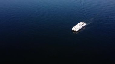 Deniz suyunda yüzen beyaz teknenin havadan görünüşü.