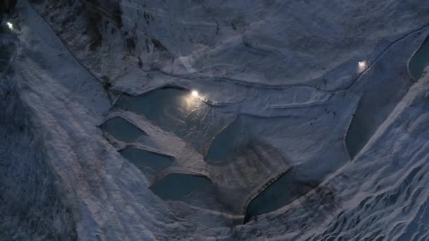 Aerial view of natural travertine pools and terraces with lights in the evening. — Stock Video