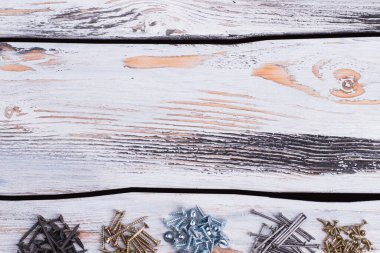Tahta arka planda çeşitli vida ve çivi türleri.