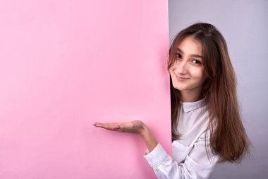 Young girl presenting copy space on a pink wall.
