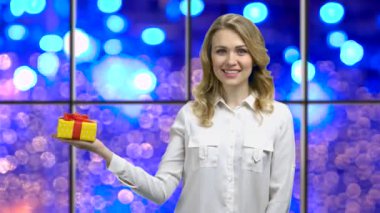 Woman holding gift box on bokeh lights background.