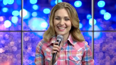 Young happy woman talking into microphone.