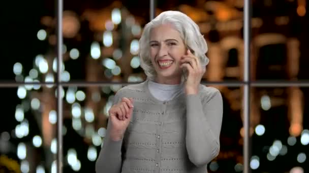 Joyful senior woman talking on futuristic phone. — Stock Video