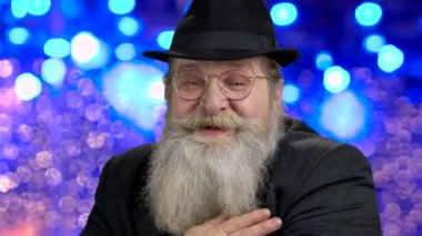 Close up senior bearded man talking to camera.