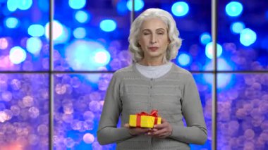 Happy mature woman presenting gift box.