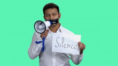 Silenced man with megaphone on color background.