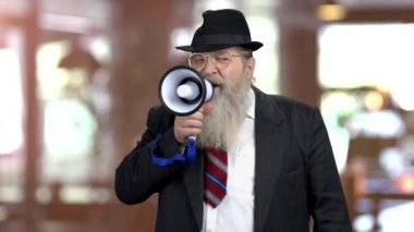 Old serious businessman talking into loudspeaker.