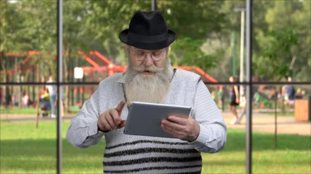 Senior bearded man using digital tablet outdoor. — стоковое видео