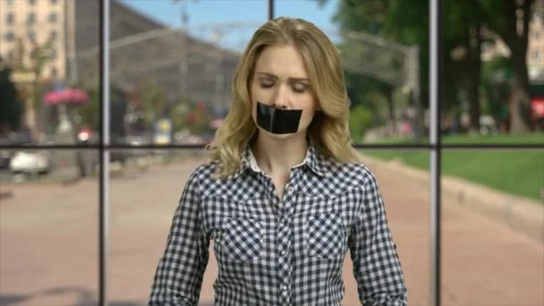 Angry woman with taped mouth looking at camera. — ストック動画