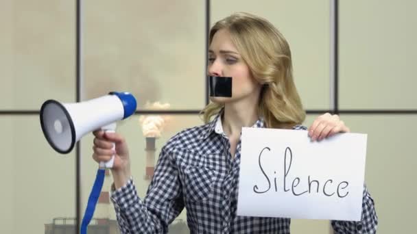Woman with taped mouth trying to speak into megaphone. — Vídeos de Stock