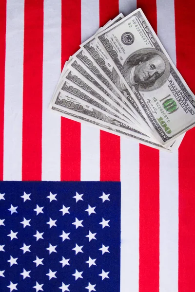 Vertical shot of the usa flag and dollar banknotes.