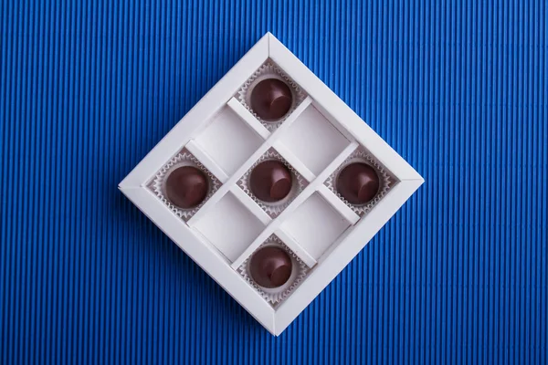 Five brown chocolate candies in the box on blue background. — Fotografia de Stock