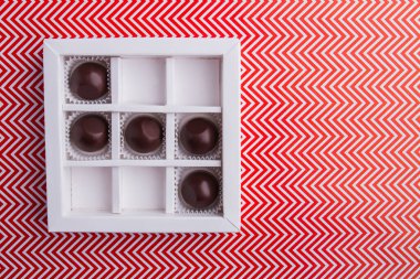 White square box with round chocolate candies.
