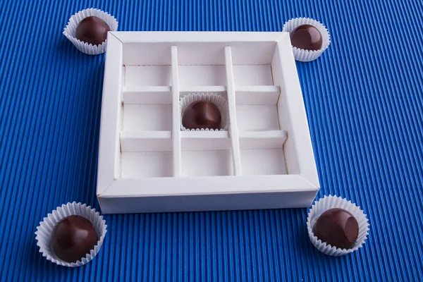 White chocolate box with brown candies on blue background. — Fotografia de Stock