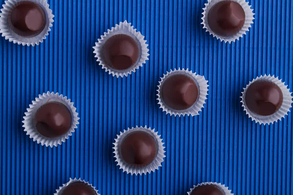 Top view flat lay round brown chocolate candies on blue background. — 图库照片
