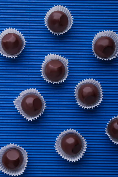 Vertical shot sweet brown chocolate candies on blue background. — 图库照片