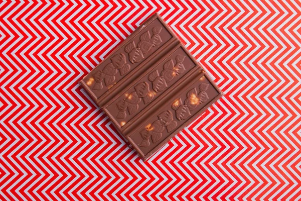 Close-up piece of brown chocolate bar with red and white background. — Fotografia de Stock