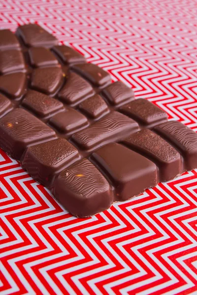 Vertical shot brown chocolate bar on white and red background. — Fotografia de Stock