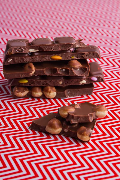 Vertical shot cut pieces of chocolate bar with hazelnuts and fruits. — Fotografia de Stock