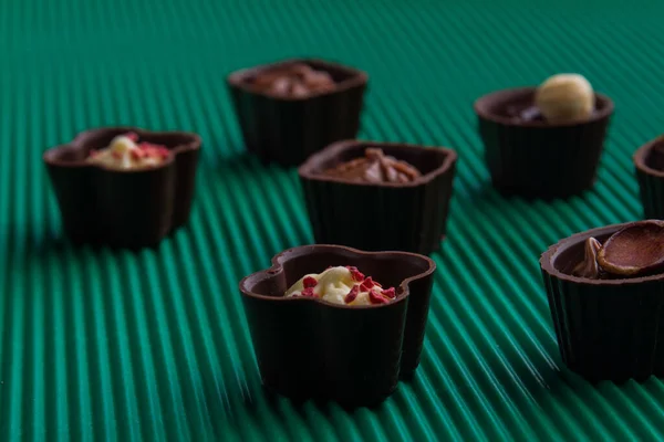 Close-up sweet chocolate candies on relief green background. — Fotografia de Stock