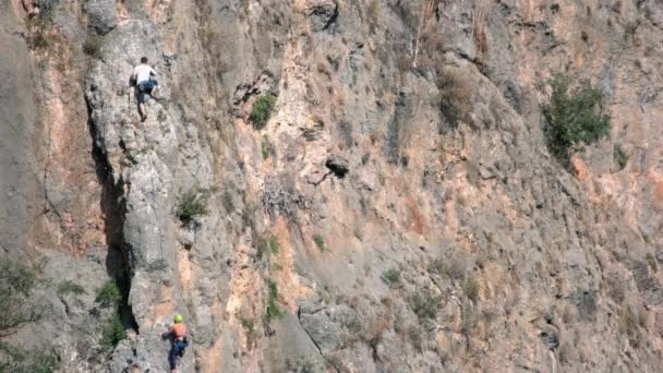 高い岩の形成を登る登山アルピニストのバックビュー. — ストック動画