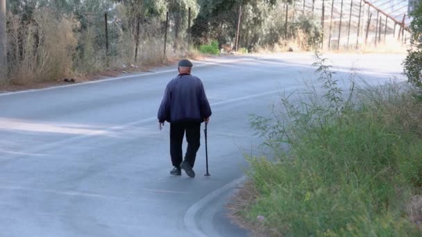 Επιστροφή άποψη του γέρου με ένα ραβδί περπάτημα κάτω από το δρόμο. — Αρχείο Βίντεο