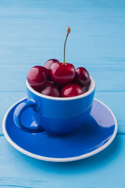 Вертикальный снимок синей чашки со свежими красными вишнями. — стоковое фото