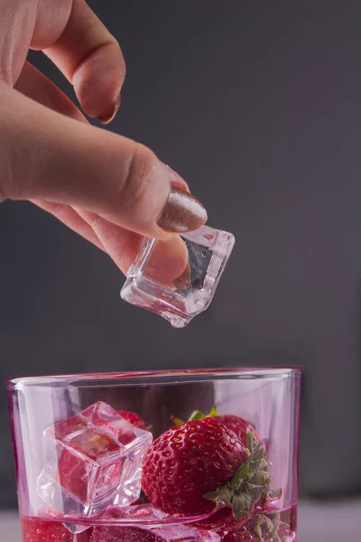 Zbliżenie samica układa kostkę lodu w szklance truskawek. — Zdjęcie stockowe