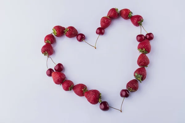 Red fresh strawberries and cherries in the shape of heart. — Stock Photo, Image