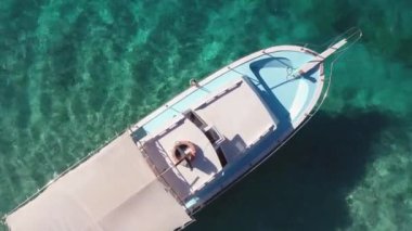 Turkuaz deniz suyundaki beyaz teknenin havadan görüntüsü..