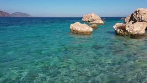 Skaliste wybrzeże i morze z krystalicznie czystą błękitną wodą. Kamienne tło plaży. — Wideo stockowe