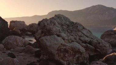 Güzel kayalık kayalıklar ve arkasında dağlar olan berrak okyanus suyu..