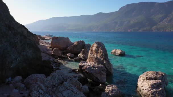 Spectaculair zeelandschap van rotsachtige kust met kristalhelder water en bergen op de achtergrond. — Stockvideo