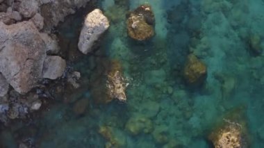 Turkuaz okyanus suyuyla kayalık kıyı manzarası.