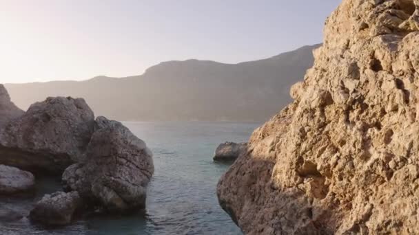 Ogromne skały w błękitnym falującym morzu. Góry w tle. — Wideo stockowe