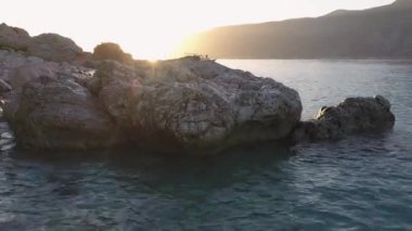 Kayalar ve turkuazlı temiz su kıyısı. Tropikal adada güzel gün batımı.