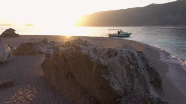 Gün batımında kayalık ada denizinde bir tekne. Yaz deniz manzarası.