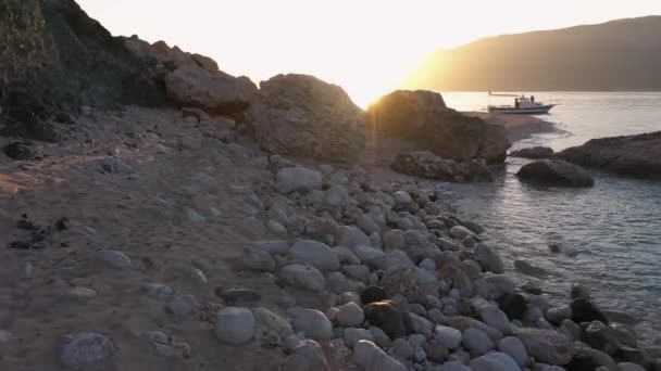 Nádherný výhled na skalnaté pobřeží a klidné moře s výhledem na hory pod západem slunce. — Stock video