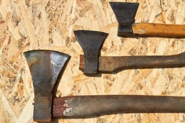 Kontrplak arka planında üç eski paslı balta aracı.