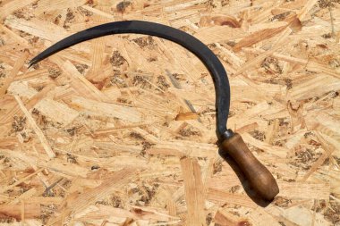 Ahşap bir arka planda eski paslı bir orak..