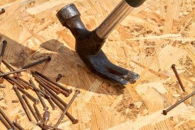 Kontrplak yüzeyinde yakın plan çiviler ve metalik çiviler.